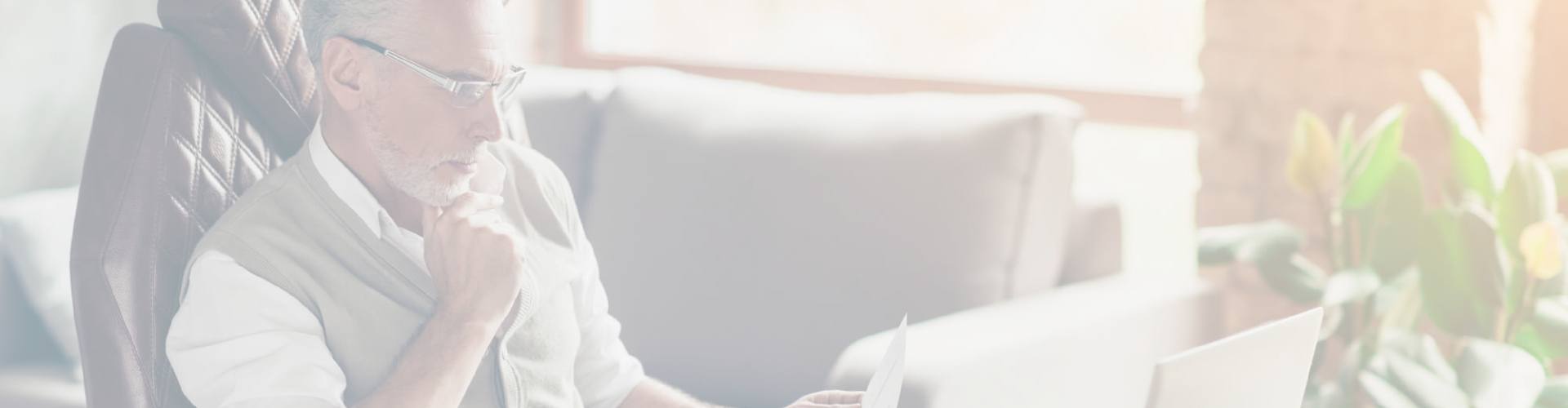retraité qui lit son attestation de retraite devant son ordinateur